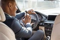 Young businessman driver sitting inside pushing horn smiling cheerful car back seat view Royalty Free Stock Photo