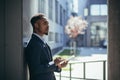 Young african american businessman in formal business suit standing working with tablet in hands on background modern office Royalty Free Stock Photo