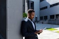 Young african american businessman in formal business suit standing working with tablet in hands on background modern office Royalty Free Stock Photo