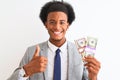 Young african american businessman holding dollars standing over isolated white background happy with big smile doing ok sign, Royalty Free Stock Photo