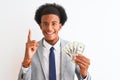 Young african american businessman holding dollars standing over isolated white background surprised with an idea or question Royalty Free Stock Photo