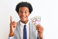 Young african american businessman holding dollars standing over isolated white background surprised with an idea or question Royalty Free Stock Photo