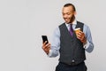 Young African-american Businessman holding Phone And Coffee to go over light grey background Royalty Free Stock Photo