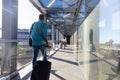 Young african american businessman with luggage walking behind businesswoman at airport corridor Royalty Free Stock Photo