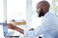 Young african american businessman pointing his finger and working on a laptop in an office alone at work. One male Royalty Free Stock Photo