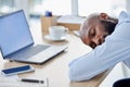 Young african american businessman sleeping at his desk at work. Tired male businessperson using a laptop while and