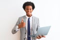 Young african american businessman using laptop standing over isolated white background happy with big smile doing ok sign, thumb Royalty Free Stock Photo