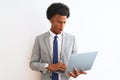 Young african american businessman using laptop standing over isolated white background scared in shock with a surprise face, Royalty Free Stock Photo