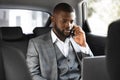 Young african businessman using mobile phone and laptop in car Royalty Free Stock Photo