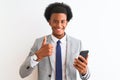 Young african american businessman using smartphone over isolated white background happy with big smile doing ok sign, thumb up Royalty Free Stock Photo