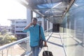 Young african american businessman walking with luggage while talking on smartphone at airport Royalty Free Stock Photo