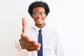 Young african american businessman wearing tie and glasses over isolated white background smiling friendly offering handshake as Royalty Free Stock Photo