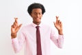 Young african american businessman wearing tie standing over isolated white background gesturing finger crossed smiling with hope