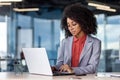 A young African-American businesswoman is sitting at a desk in the office and is concentrating on working on a laptop Royalty Free Stock Photo