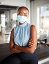 Young african american businesswoman standing with her arms crossed and wearing a mask at work. One confident black Royalty Free Stock Photo