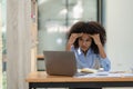 Young african american businesswoman thinking and stressed while working on laptop and financial documents Royalty Free Stock Photo