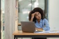 Young african american businesswoman thinking and stressed while working on laptop and financial documents Royalty Free Stock Photo