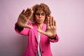 Young african american businesswoman wearing glasses standing over pink background doing frame using hands palms and fingers, Royalty Free Stock Photo