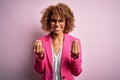 Young african american businesswoman wearing glasses standing over pink background doing money gesture with hands, asking for Royalty Free Stock Photo