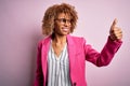 Young african american businesswoman wearing glasses standing over pink background Looking proud, smiling doing thumbs up gesture Royalty Free Stock Photo