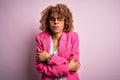 Young african american businesswoman wearing glasses standing over pink background shaking and freezing for winter cold with sad