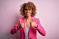 Young african american businesswoman wearing glasses standing over pink background success sign doing positive gesture with hand, Royalty Free Stock Photo