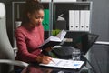 Young African-American businesswoman working with documents and notebook at computer Desk in office Royalty Free Stock Photo