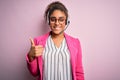 Young african american call center agent girl wearing glasses working using headset doing happy thumbs up gesture with hand Royalty Free Stock Photo