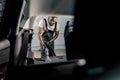 Young African American car wash service worker, doing wet cleaning of luxurious vehicle luggage trunk using vacuum