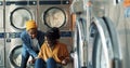 Young African American cheerful couple having fun in laundry service room. Pretty happy girl sitting in carriage and guy Royalty Free Stock Photo