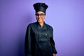 Young african american chef girl wearing cooker uniform and hat over purple background smiling looking to the side and staring Royalty Free Stock Photo