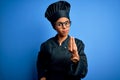 Young african american chef woman wearing cooker uniform and hat over blue background Doing Italian gesture with hand and fingers Royalty Free Stock Photo