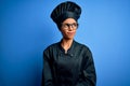 Young african american chef woman wearing cooker uniform and hat over blue background smiling looking to the side and staring away Royalty Free Stock Photo