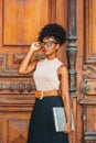 Young African American College Student with afro hairstyle, eye glasses, wearing sleeveless light color top, black skirt, belt, Royalty Free Stock Photo