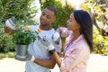 Young african american couple planting flowers while gardening together at backyard