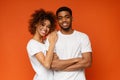 Young african-american couple posing on orange background