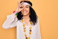 Young african american curly hippie woman wearing sunglasses and vintage accessories doing ok gesture with hand smiling, eye