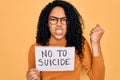 Young african american curly woman holding banner with no to suicide message annoyed and frustrated shouting with anger, crazy and