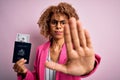 Young african american curly woman holding united states passport with dollars banknotes with open hand doing stop sign with Royalty Free Stock Photo