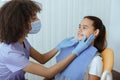 Young african american dentist in uniform, protective mask and gloves examination patients mouth to prevent caries