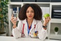 Young african american dietitian woman holding fresh apple and water looking at the camera blowing a kiss being lovely and sexy Royalty Free Stock Photo