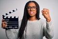 Young african american director girl filming a movie using clapboard over isolated background annoyed and frustrated shouting with Royalty Free Stock Photo