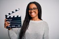 Young african american director girl filming a movie using clapboard over isolated background with a happy face standing and Royalty Free Stock Photo