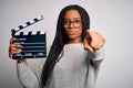 Young african american director girl filming a movie using clapboard over isolated background pointing with finger to the camera Royalty Free Stock Photo