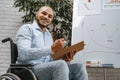 Young african american disabled man in a wheelchair makes presentation at office on whiteboard Royalty Free Stock Photo