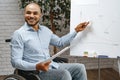 Young african american disabled man in a wheelchair makes presentation at office on whiteboard Royalty Free Stock Photo