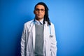 Young african american doctor man with dreadlocks wearing stethoscope and glasses with serious expression on face Royalty Free Stock Photo