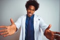 Young african american doctor man wearing coat standing over isolated white background looking at the camera smiling with open Royalty Free Stock Photo