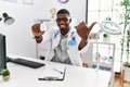 Young african american doctor man wearing doctor uniform holding prescription pills at the clinic pointing thumb up to the side Royalty Free Stock Photo