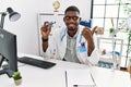 Young african american doctor man wearing doctor uniform holding thermometer at the clinic pointing thumb up to the side smiling Royalty Free Stock Photo